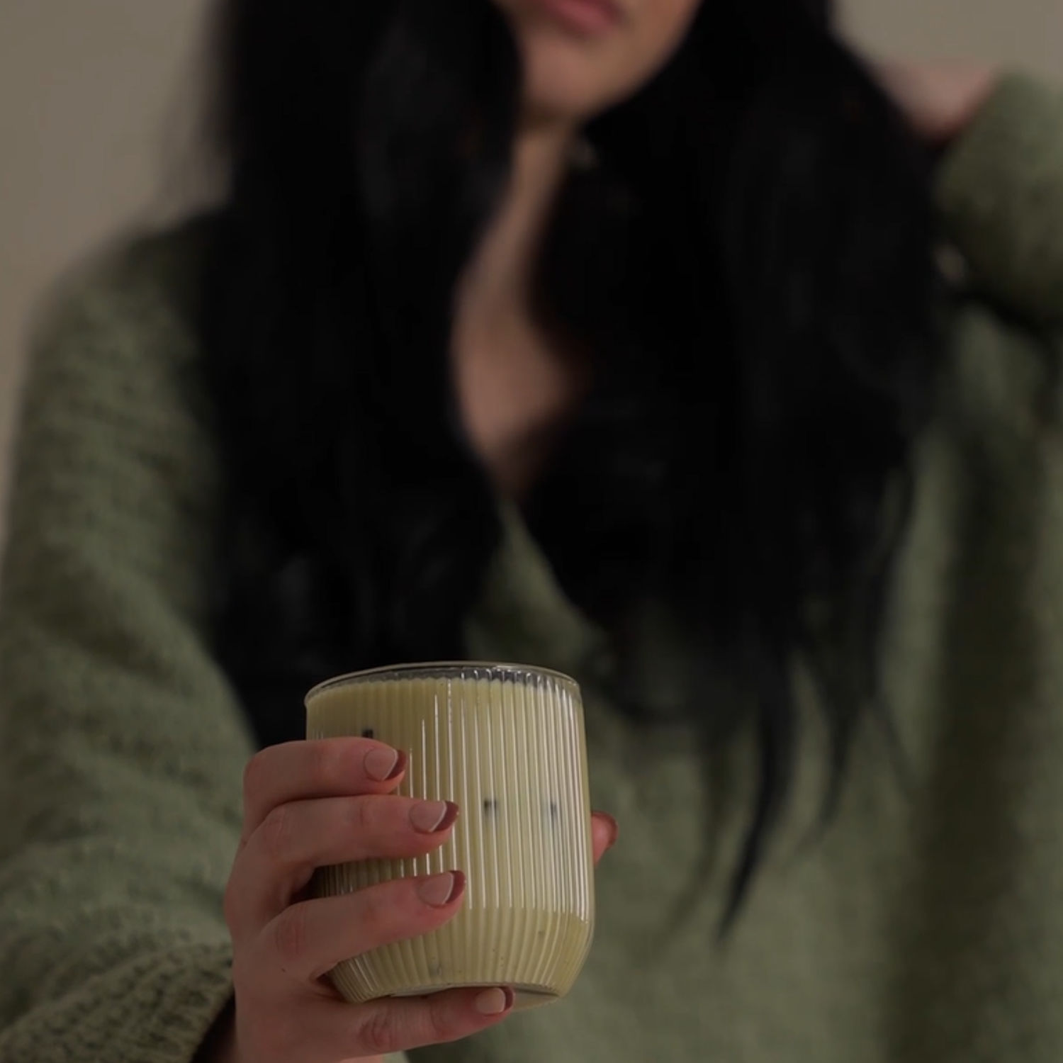 Woman in a white shirt holding a mug by the window, symbolising calm and improved wellbeing through hormone health support