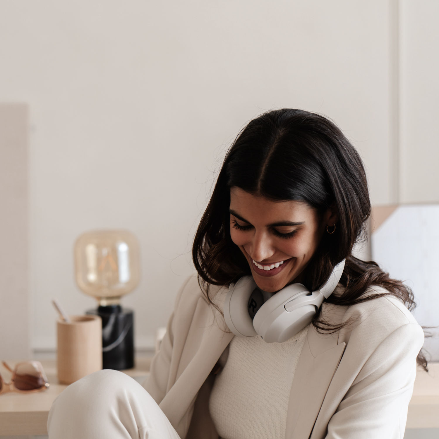 Woman in a white shirt holding a mug by the window, symbolising calm and improved wellbeing through hormone health support